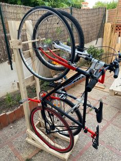 a bicycle is mounted to a wooden stand with two bicycles on it's wheels