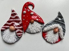 three christmas ornaments are displayed on a white surface with red and silver decorations in the shape of gnomes