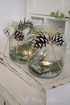 two mason jars filled with pine cones and lights