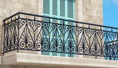 a balcony with iron railing and blue shutters