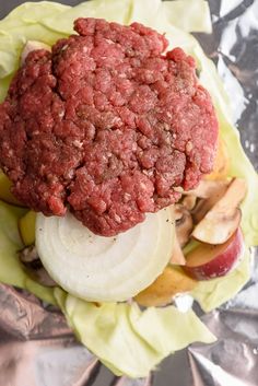 an image of a hamburger with onions and apples on the side in foil wrapper