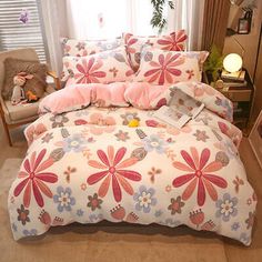 a bed with pink and blue flowers on it in a room next to a window