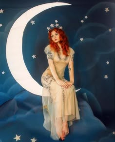 a woman with red hair sitting on the moon