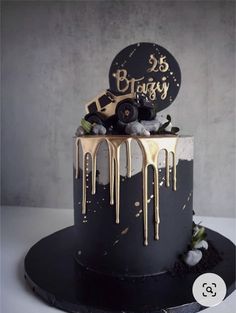 a black and white cake with gold drips on it's top is shown