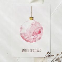 a watercolor christmas ornament hanging from a string