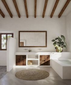 a bathroom with a sink, mirror and bathtub next to a plant in a vase