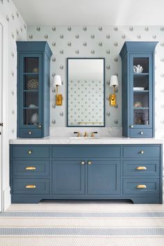 a bathroom with blue cabinets and gold accents on the wall, along with a white tiled floor