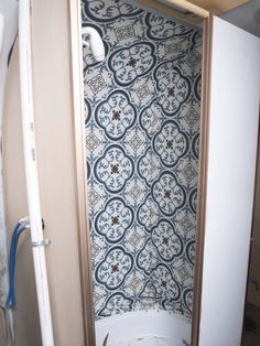 a bathroom with a toilet and bathtub next to a wallpapered shower stall