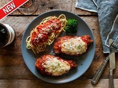 two chicken parmesan with spaghetti and broccoli on a plate next to a glass of wine