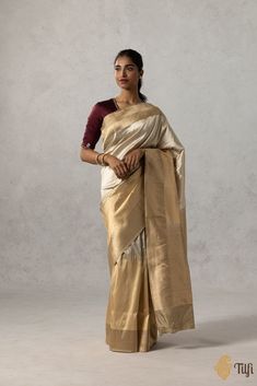 "A lustrous pure Katan silk saree in a\u00a0harmonious\u00a0combination of\u00a0beige and gold.\u00a0Its plain body is\u00a0edged with an ornately handwoven border,\u00a0depicting\u00a0a medley of floral vines, geometric patterns, and a\u00a0dynamic\u00a0rendition of lines of varying widths.\u00a0\n\n\nColor\u00a0- Elegant shades of\u00a0Beige and\u00a0Gold\n\nFabric\u00a0-\u00a0Soft as butter, pure Katan silk\u00a0\n\nTechnique\u00a0-  An enduring Kadwa weave. The elaborate and laborious Kadwa (Kadhua) technique involves hand-weaving each motif separately. It takes longer on the handloom, but makes a more robust pattern, which stands out on the fabric.\n\n\nTilfi Promise\u00a0- Pure. Handloom. Banaras.\n\nNote\u00a0- The saree comes with its own blouse piece. The\u00a0model is wearing a s Luxury Katan Silk Cream Saree, Luxury Beige Saree With Zari Weaving, Luxury Cream Katan Silk Saree, Luxury Gold Katan Silk Pre-draped Saree, India Inspired, Katan Silk Saree, Katan Silk, Shades Of Beige, Gold Fabric