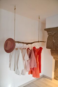 clothes hanging on a rope in front of a fire place with a hat and other items