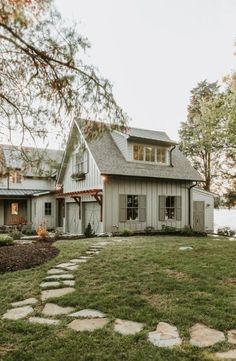 a white house sitting on top of a lush green field next to a lake and trees