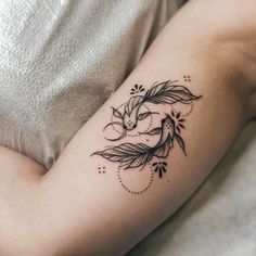 a woman's arm with a bird and leaves tattoo on the left side of her arm