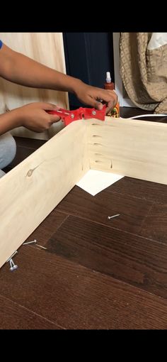 a person is working on some kind of wooden structure with pliers and screwdrivers