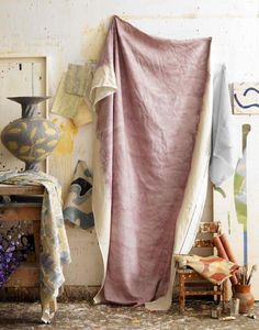 a room with various items on the floor and walls, including a pink blanket draped over a chair