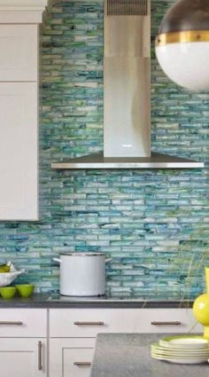 a kitchen with white cabinets and blue glass backsplash