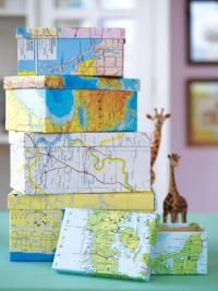 a giraffe is standing in front of a stack of books with maps on it