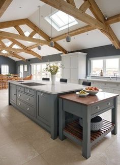 a large kitchen with an island in the center and skylights above it, along with wooden beams