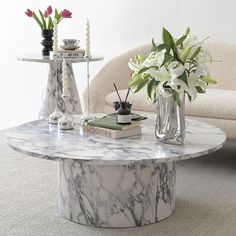 a marble coffee table with vases and flowers on it