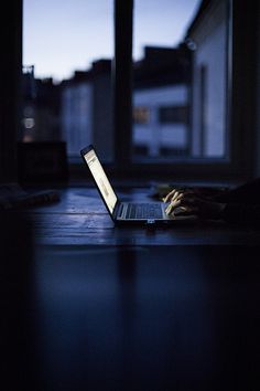 a laptop computer sitting on top of a wooden table in front of a large window