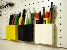 several pens and pencils are placed in a holder on the wall next to each other