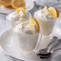 two cups filled with ice cream and topped with sliced oranges on a white plate