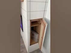 an open cabinet in the corner of a room with tile walls and flooring on it