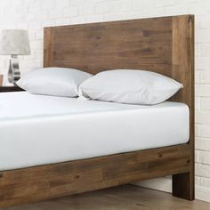 a bed with white pillows and wooden headboard