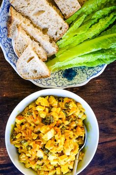 two bowls of food on a table with bread and asparagus next to them