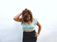 a woman standing in front of a white wall with her hands on her head and looking down