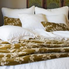 an unmade bed with white pillows and green comforter on top of it's headboard