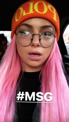 a woman with pink hair wearing glasses and a beanie on top of her head