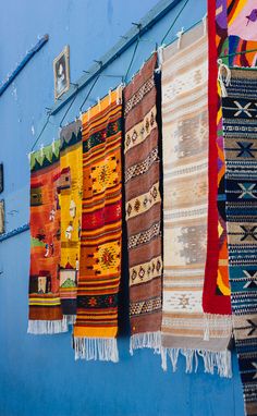 many colorful rugs hanging on a blue wall