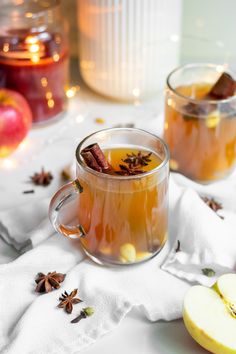 two mugs filled with apple cider on top of a table