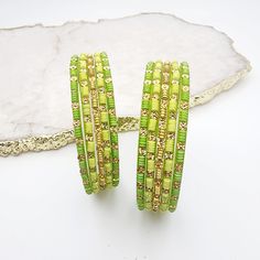 Brighten your collection with this distinctive glass bangle set, featuring two stunning shades of green. The set includes a vivid neon green with an electrifying glow and a rich forest green with unique embossed details. This combination brings a bold and fresh vibrancy to your look, perfect for making a standout statement. *To prevent any potential damage, please put on each glass bangle individually. For a snug fit, we suggest sizing up from your usual bangle size. *bangles are final sale Green Beaded Bracelets For Festive Occasions, Festive Green Beaded Bangle Bracelets, Bohemian Green Bracelets For Festive Occasions, Green Bohemian Bangle For Parties, Bohemian Green Beaded Bracelets For Parties, Adjustable Green Bangle For Party, Adjustable Green Bangle Jewelry, Green Bohemian Bangle Jewelry, Bohemian Green Bangle Jewelry