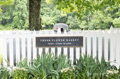 there is a sign that says fresh flower market in front of a white picket fence