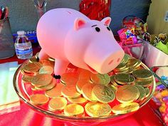 a pink pig sitting on top of a pile of gold coins