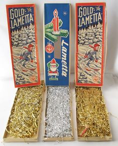 three boxes with gold lametta on them sitting next to each other in tinsel