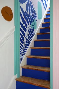 a blue and white staircase leading up to a wall with an abstract design on it