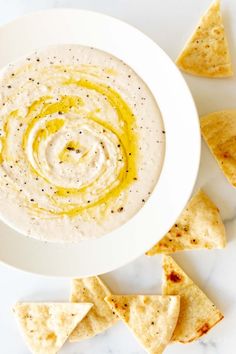 a white bowl filled with dip and tortilla chips