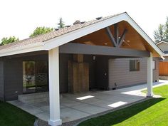 a covered patio with an attached carport in the middle of a lawn area next to a house