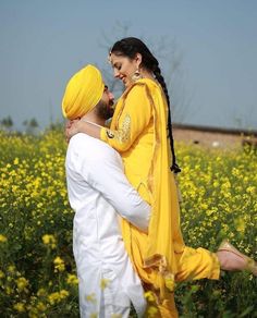 a man and woman standing in a field with yellow flowers