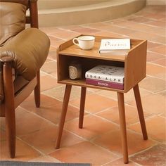 a small wooden table with a book and cup on it sitting next to a chair