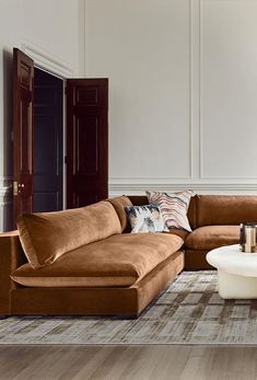 a living room with brown couches and white coffee table in front of the wall