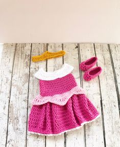 a crocheted dress and booties sitting on top of a wooden table