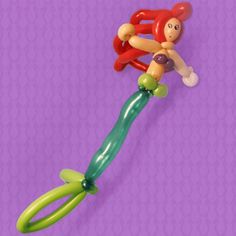 an inflatable monkey toy is on top of a purple background with green stems