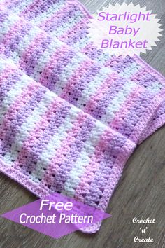 a pink and white crochet baby blanket sitting on top of a wooden floor