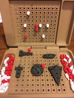 an open box filled with lots of red and white pieces on top of a wooden table