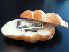 a loaf of bread with a hundred dollar bill sticking out of it's side