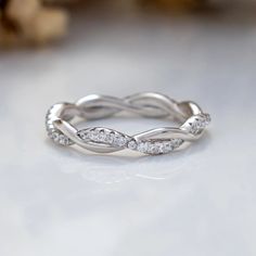 a white gold wedding ring with diamonds on it's sides, sitting on a table